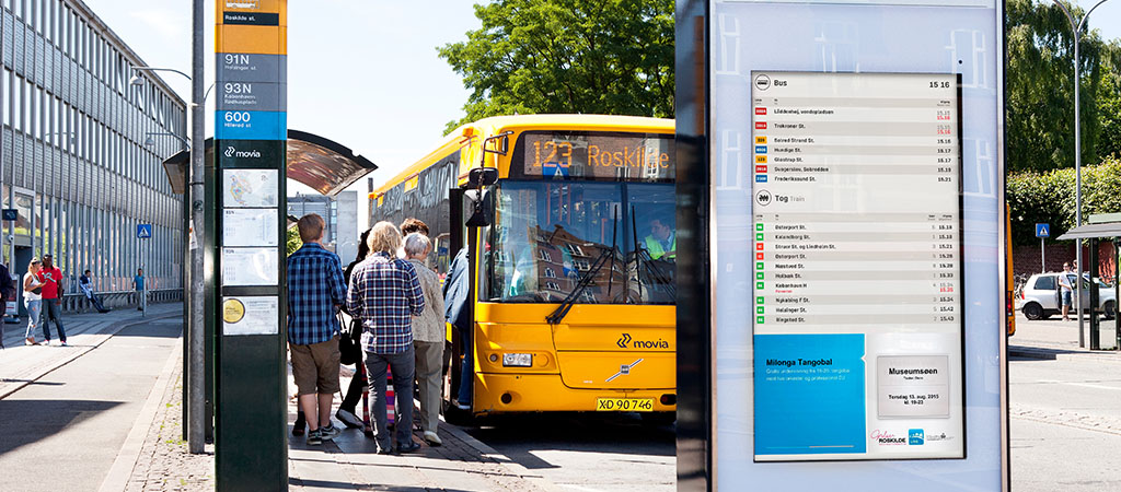 The image shows a bus at a stop in Denmark. At the stop there is pylon showing bus times.