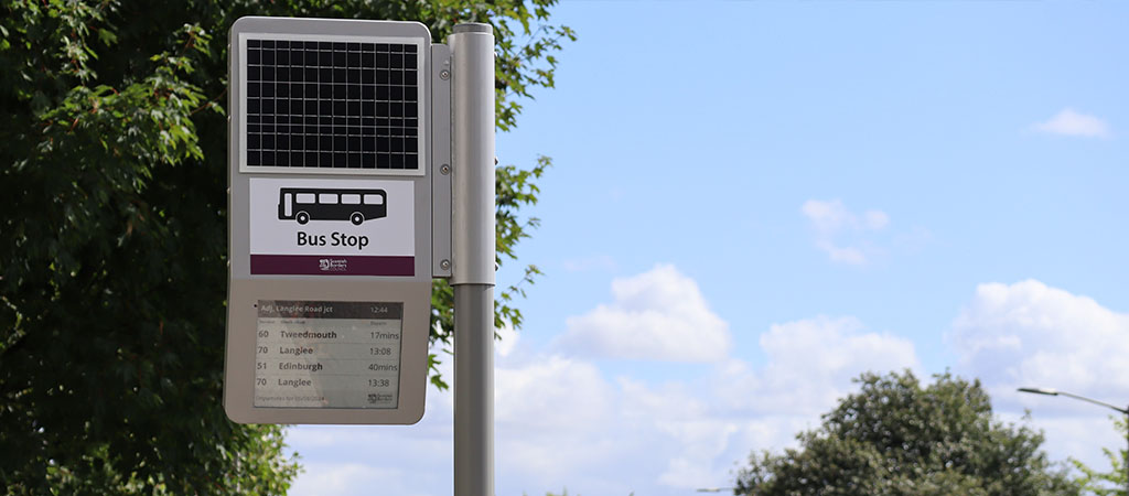 The image shows a solar-powered Journeo real time passenger information display installed in Scotland.